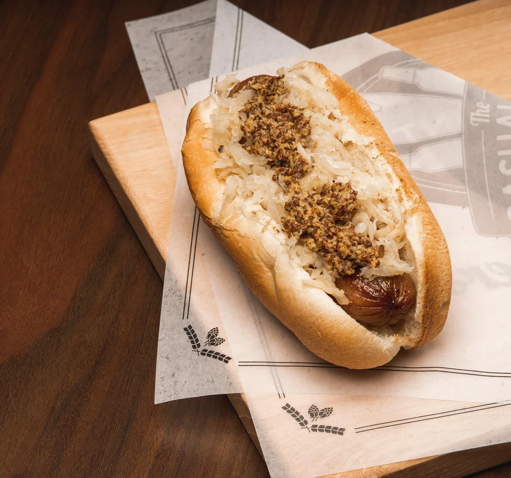 Hot dog with sauerkraut and coarse whole-grain mustard on a bun.