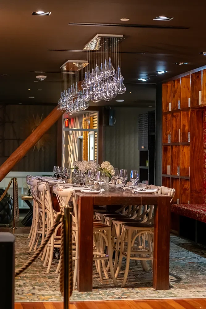 Long communal table set with elegant florals, bentwood chairs, modern chandeliers.