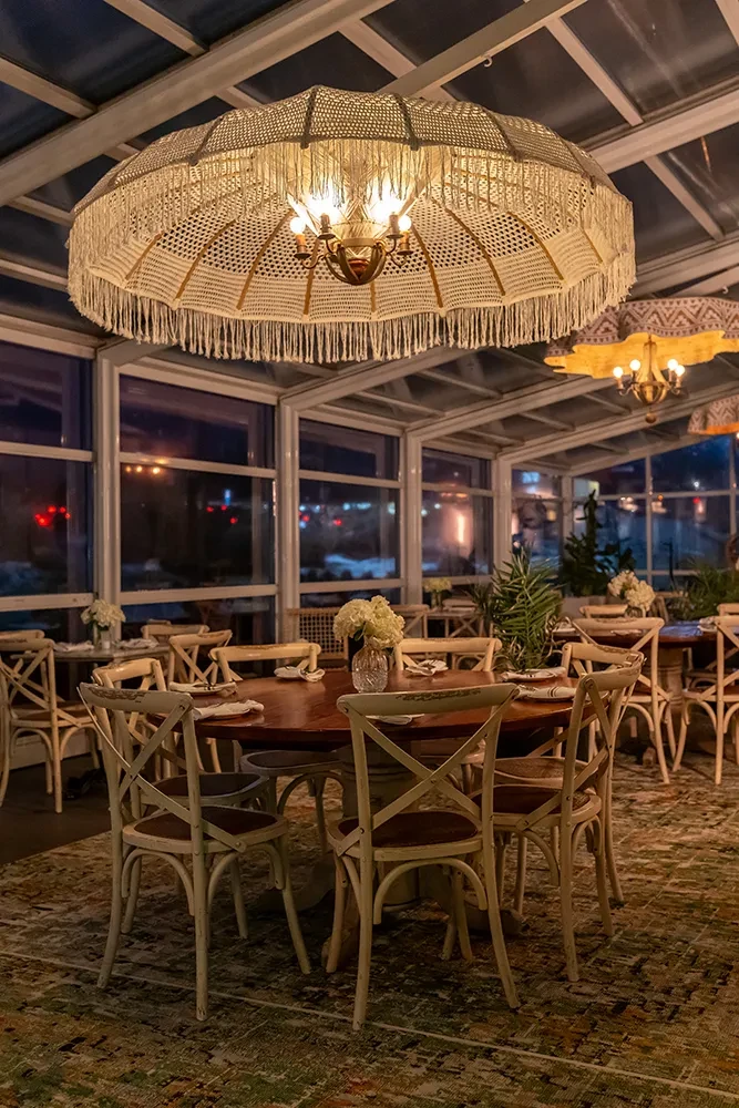 Evening restaurant interior with large macrame chandelier and glass ceiling.