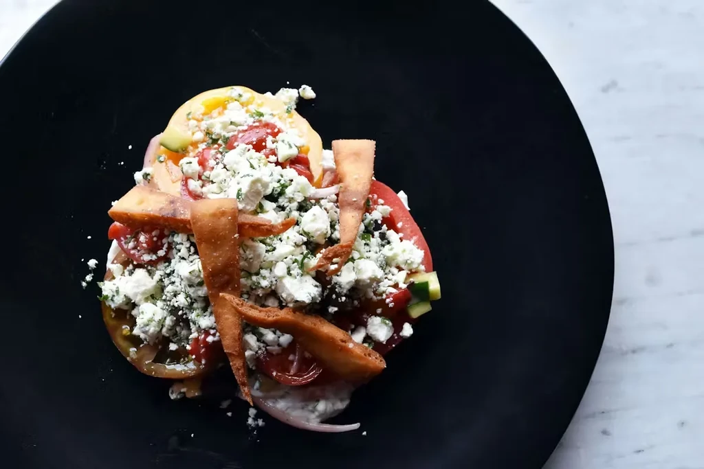 Colorful tomato salad with feta, herbs, cucumber, pita chips.