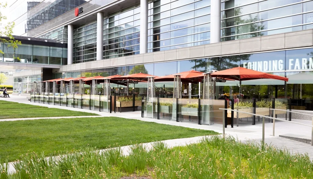 Modern Founding Farms restaurant patio with orange umbrellas and heaters.