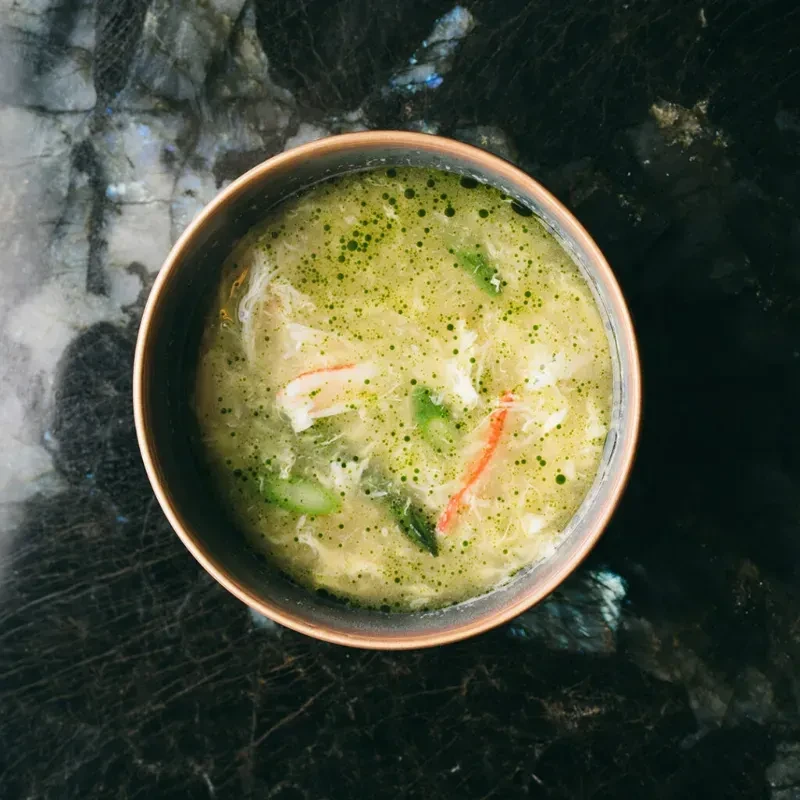 Creamy yellow-green soup with crab, lobster, and green vegetables.