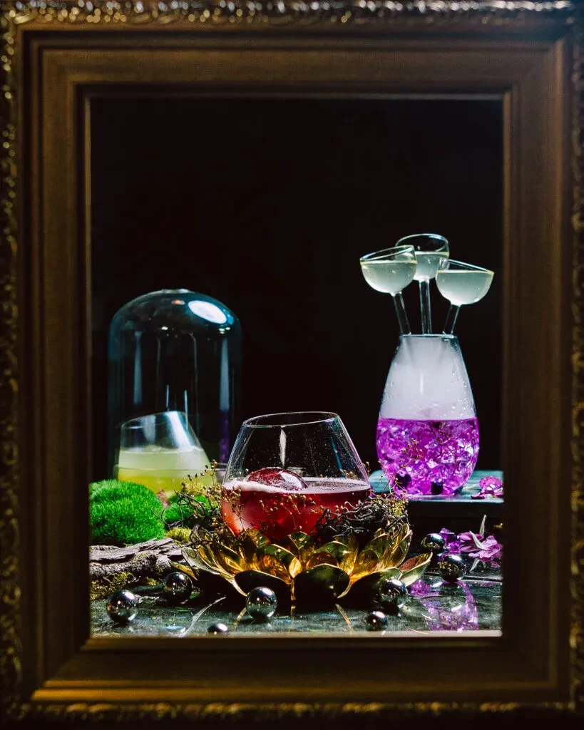 Stylized red, yellow, and purple cocktails displayed in an ornate frame.