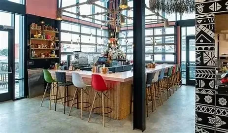 Modern bar with bamboo-textured counter, colorful stools, and patterned pillar.