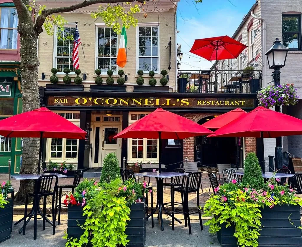 O'Connell's restaurant exterior, sunny patio with red umbrellas, flowers, and flags.