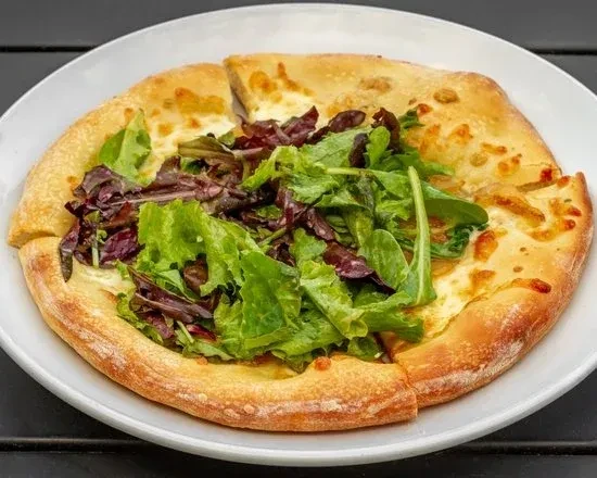 Close-up of golden flatbread topped with melted cheese and fresh greens.
