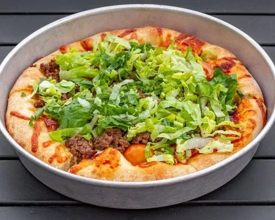 Overhead taco pizza with ground beef, shredded lettuce, and diced tomatoes.