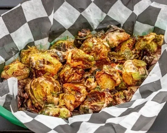 Roasted Brussels sprouts with creamy sauce in a checkered-lined container.