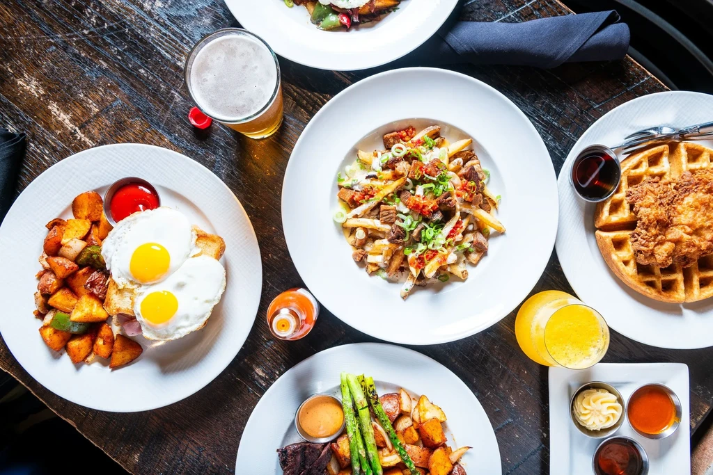Top-down view of a dark wooden table with various brunch dishes.