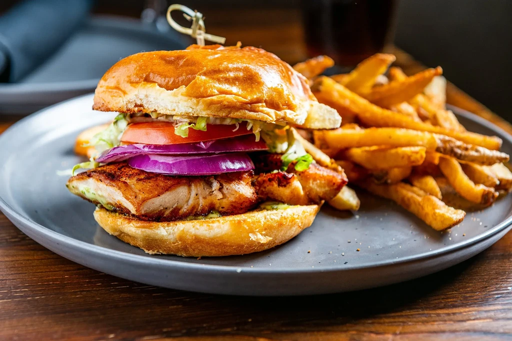 Grilled fish/chicken sandwich, lettuce, tomato, onion, and fries.