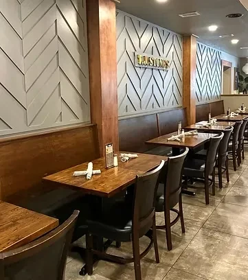 Empty T.J. STONES restaurant interior with patterned walls, booths, and tables.