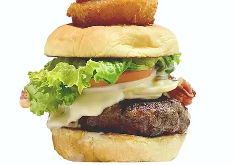 Stacked gourmet burger with beef, cheese, bacon, vegetables, and onion ring.