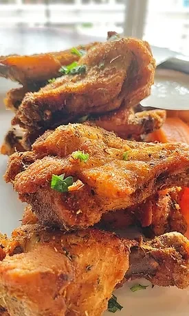 Close-up of stacked, crispy golden-brown fried food with green herbs.