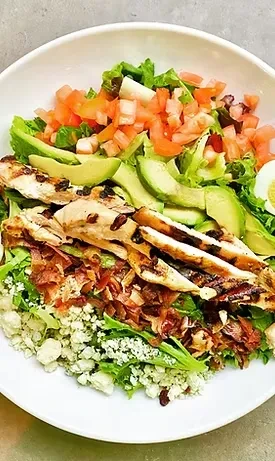 Close-up of a vibrant Cobb salad with chicken, avocado, bacon, and egg.