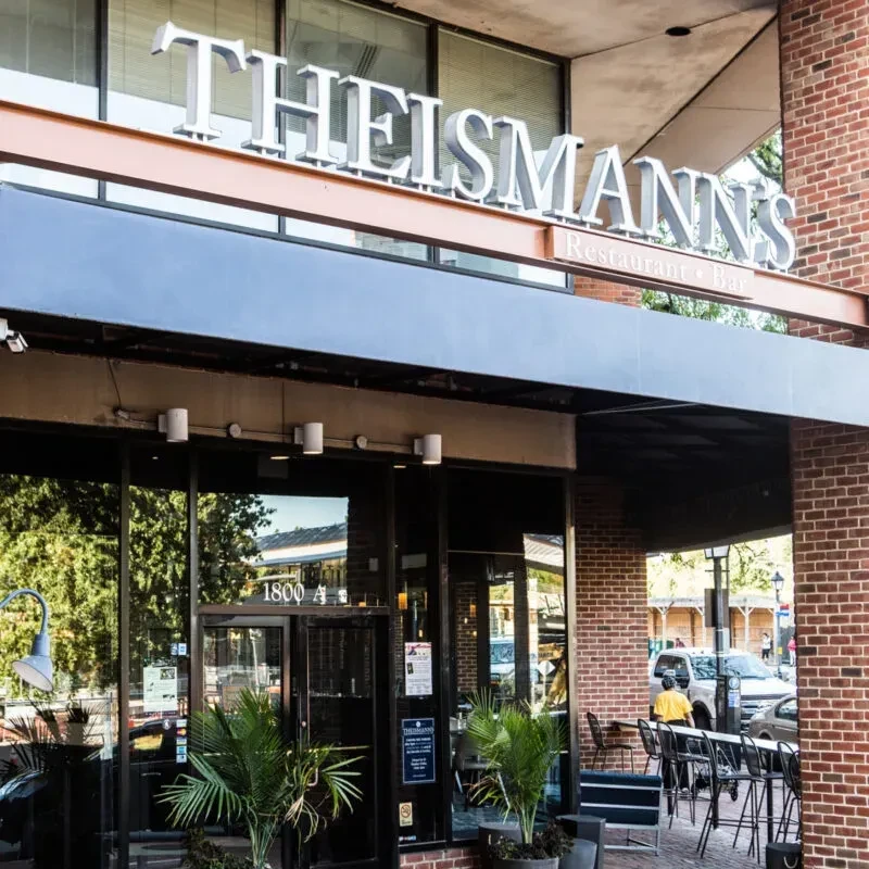 THEISMANN'S Restaurant + Bar exterior with brick facade and outdoor seating.
