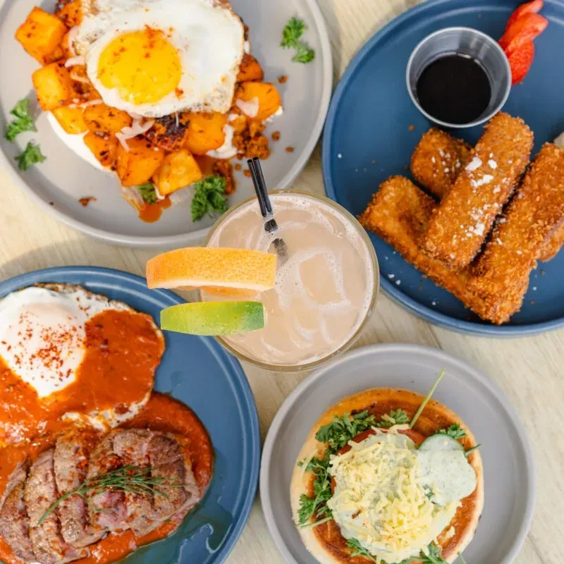 Flat lay of a vibrant brunch spread with four dishes and a drink.