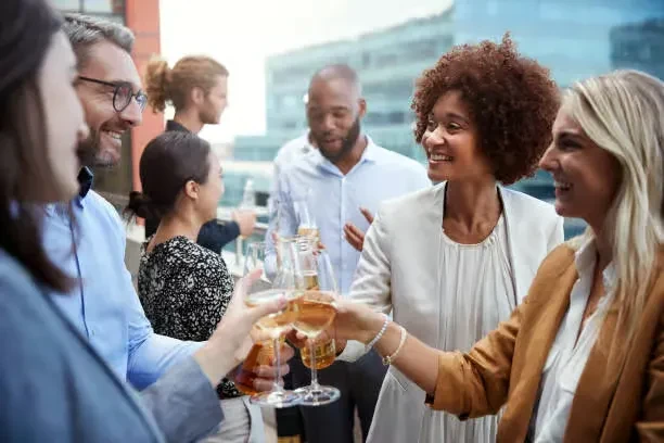 Smiling diverse group raising glasses for a toast on an outdoor terrace.