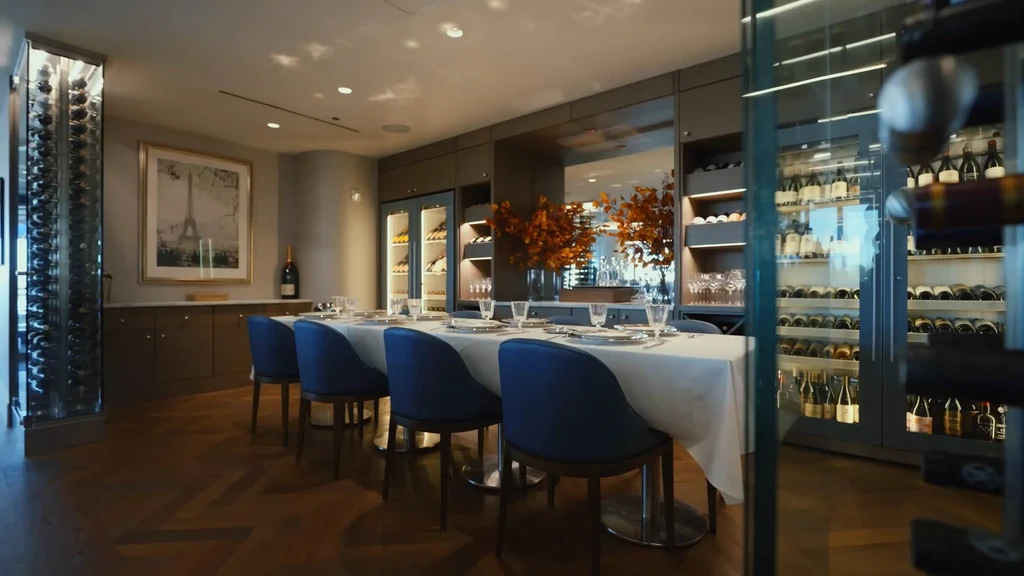 Elegant private dining room with set table, blue chairs, and wine display.