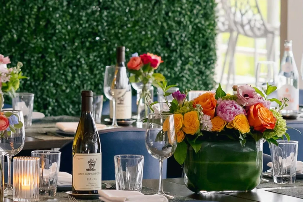 Upscale table setting with wine bottle, glasses, and colorful flowers.