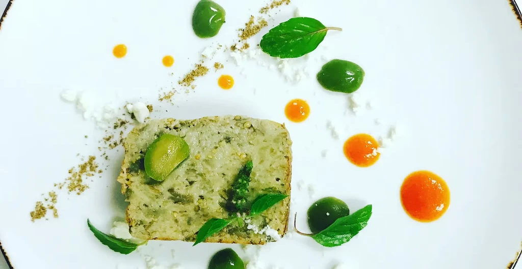 Finely plated savory loaf with sauces and garnishes.