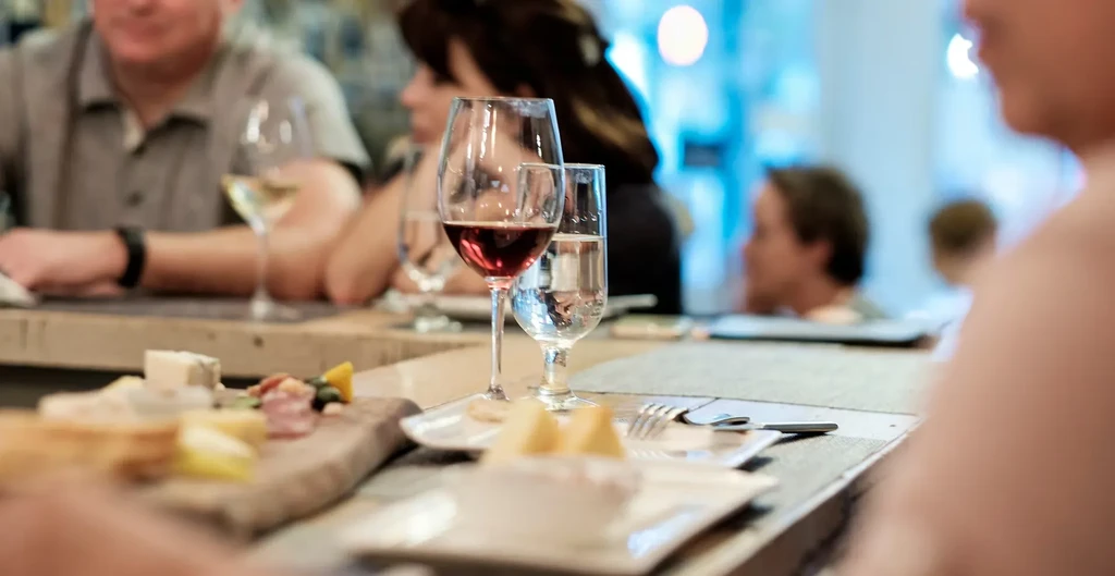 Charcuterie board with red wine and water in a lively restaurant.