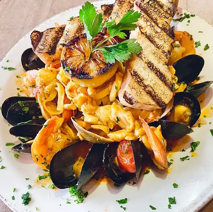 Top-down seafood pasta with mussels, shrimp, lemon, grilled bread.