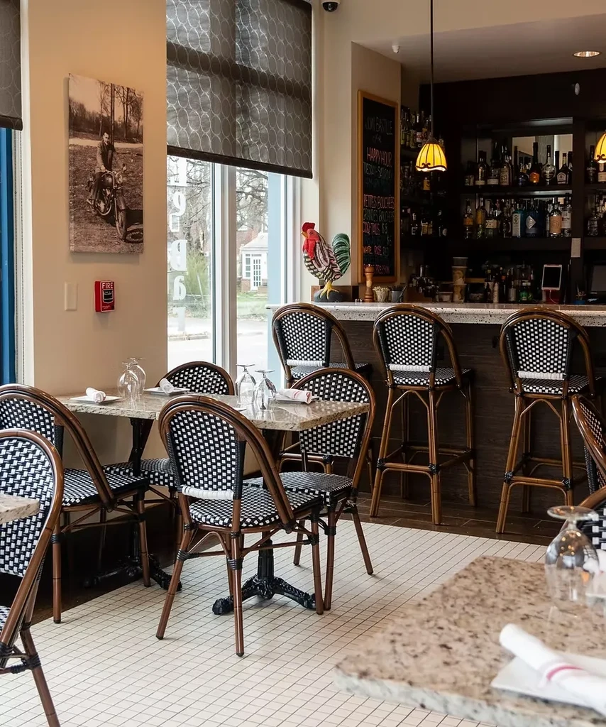 Bright restaurant interior with dining tables, a stocked bar, and natural light.