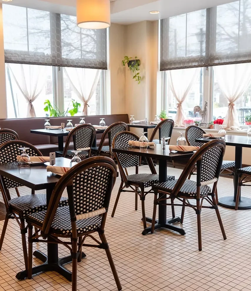 Empty, bright restaurant dining room with set tables and checkerboard chairs.
