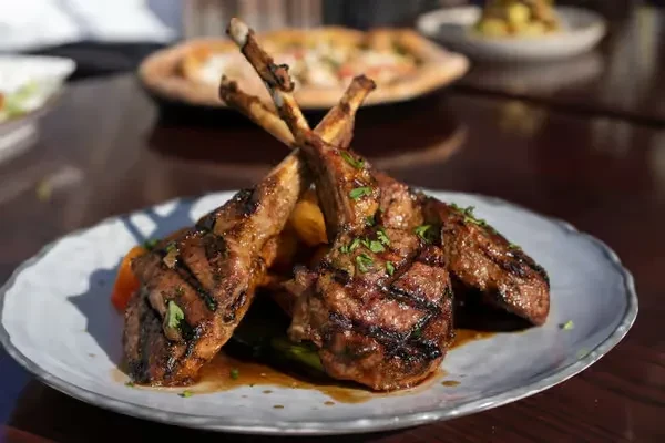 Grilled lamb chops with brown sauce, fresh herbs, and grill marks.