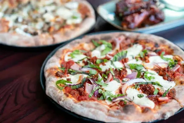 Close-up: Freshly baked pizza with spicy sausage, onions, basil.