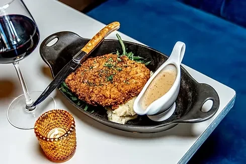 Breaded cutlet, mashed potatoes, gravy, red wine, and a lit candle.