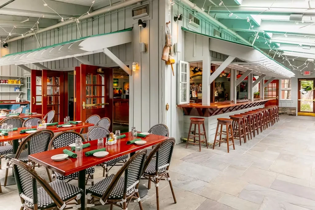 Bright restaurant with red tables, dark wood bar, and nautical decor.