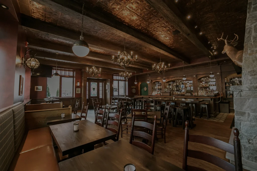 Warm, rustic restaurant and bar interior with dark wood and lodge decor.