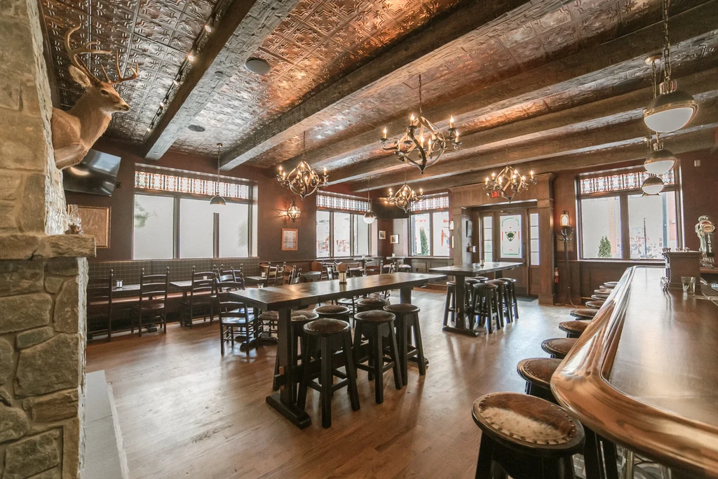 Lodge-themed restaurant interior with ornate tin ceiling, fireplace, and bar.