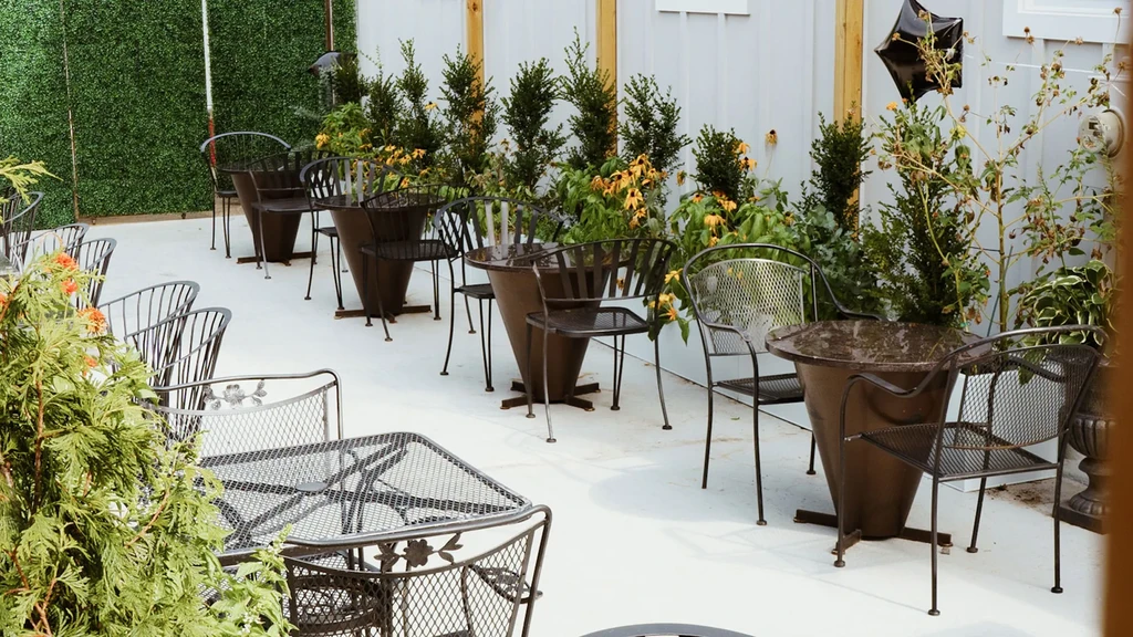 Outdoor restaurant patio with metal tables, chairs, plants, and star balloon.