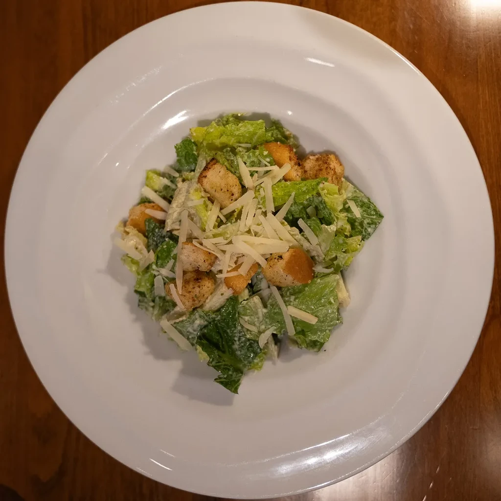 Top-down Caesar salad: romaine, croutons, Parmesan, and creamy dressing.