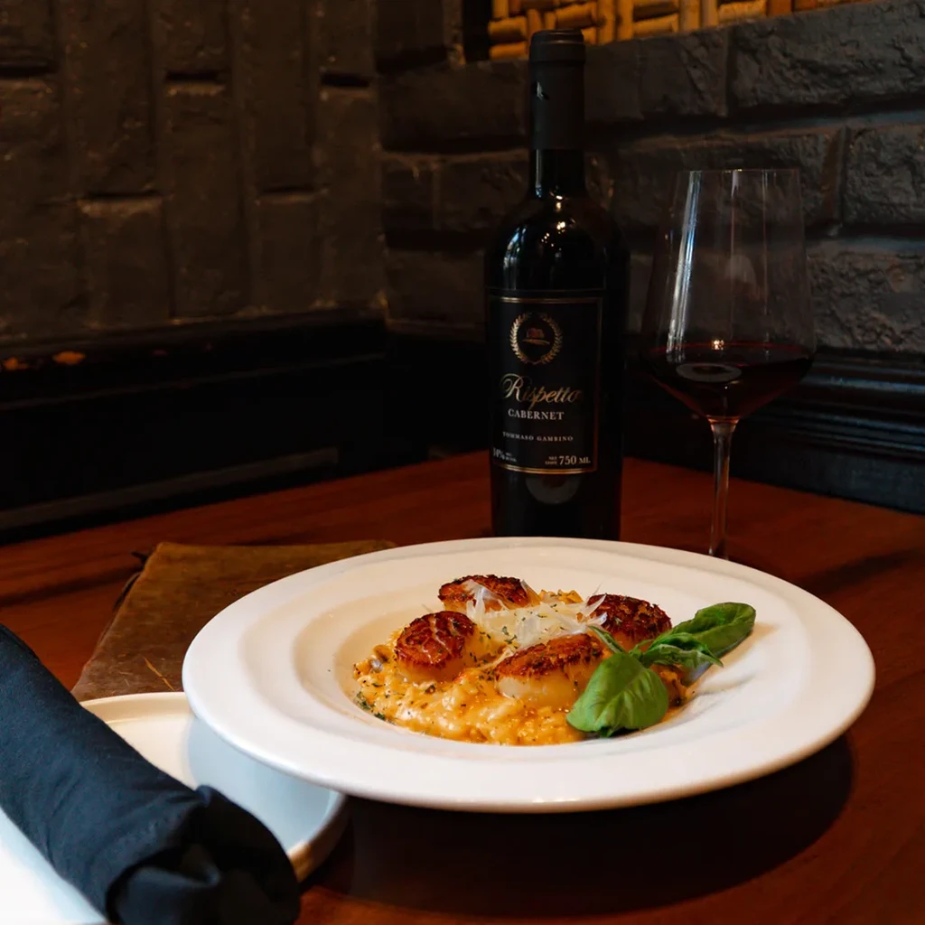 Seared scallops on risotto with cheese, basil, and red wine.