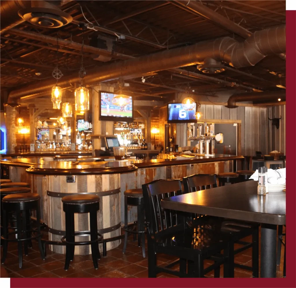 Industrial-rustic bar interior with a curving wooden bar and sports TVs.