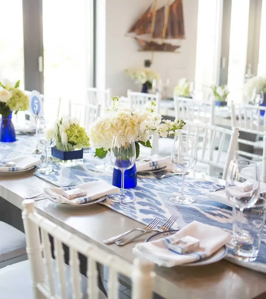 Dining table with blue ikat runner, white flowers, and ship model.