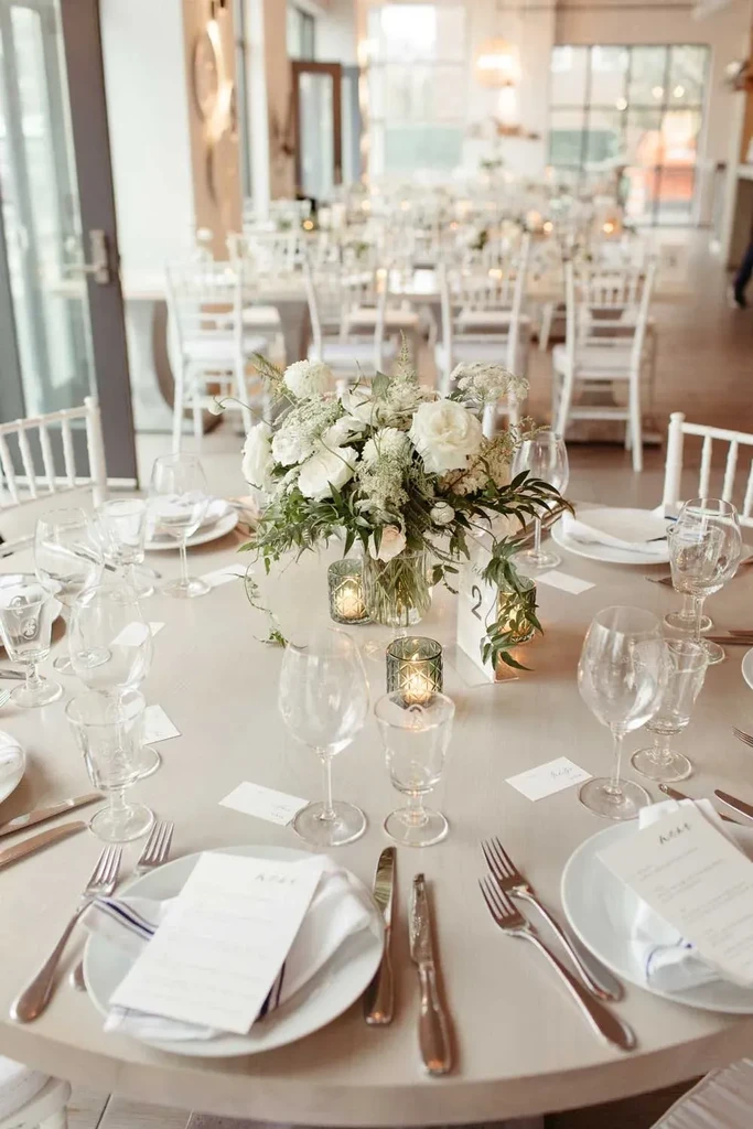 Elegantly set round table with white roses, candles, and number 2.