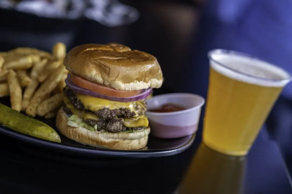 Double cheeseburger, fries, pickle, ketchup, and beer.