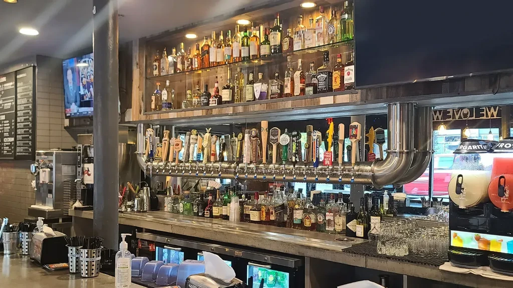 Well-lit bar with liquor bottles, beer taps, and two frozen drink machines.