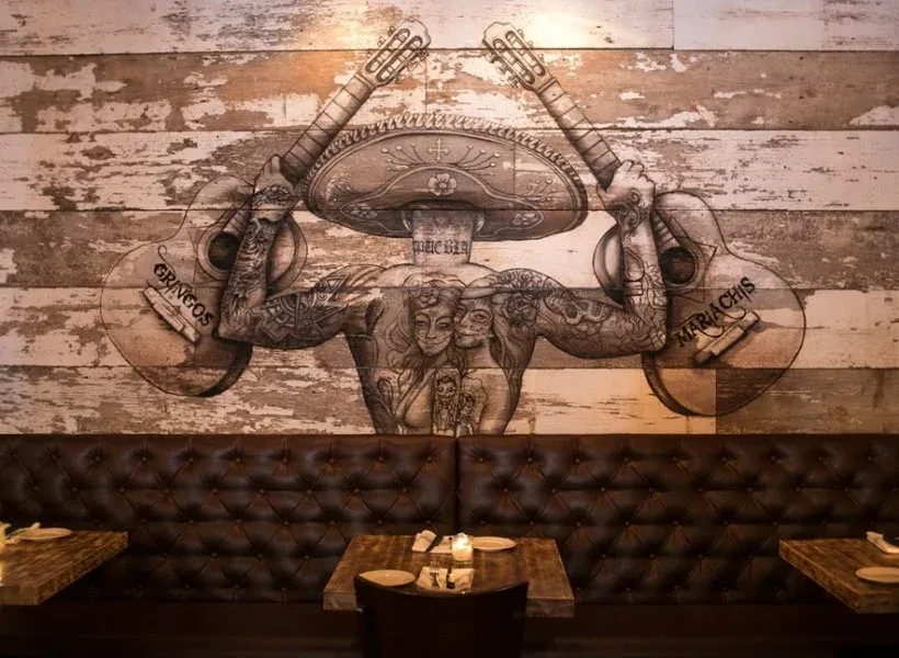 Restaurant interior with a skeletal mariachi mural and empty booths.