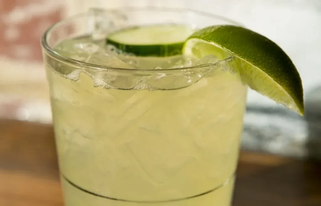 Close-up of a frosty green drink with lime and cucumber.
