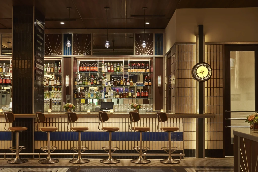 Modern Art Deco bar with stocked liquor shelves and empty stools.