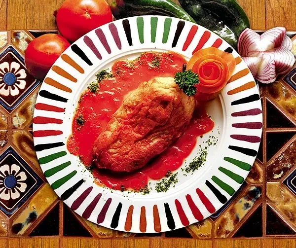 Vibrant Mexican dish with sauced entree, vegetable rose, and fresh produce.