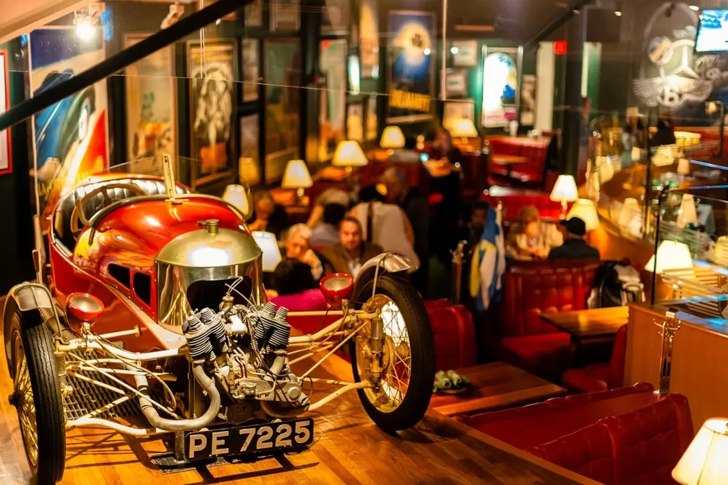 Vintage red and brass racing car with exposed engine in a restaurant.