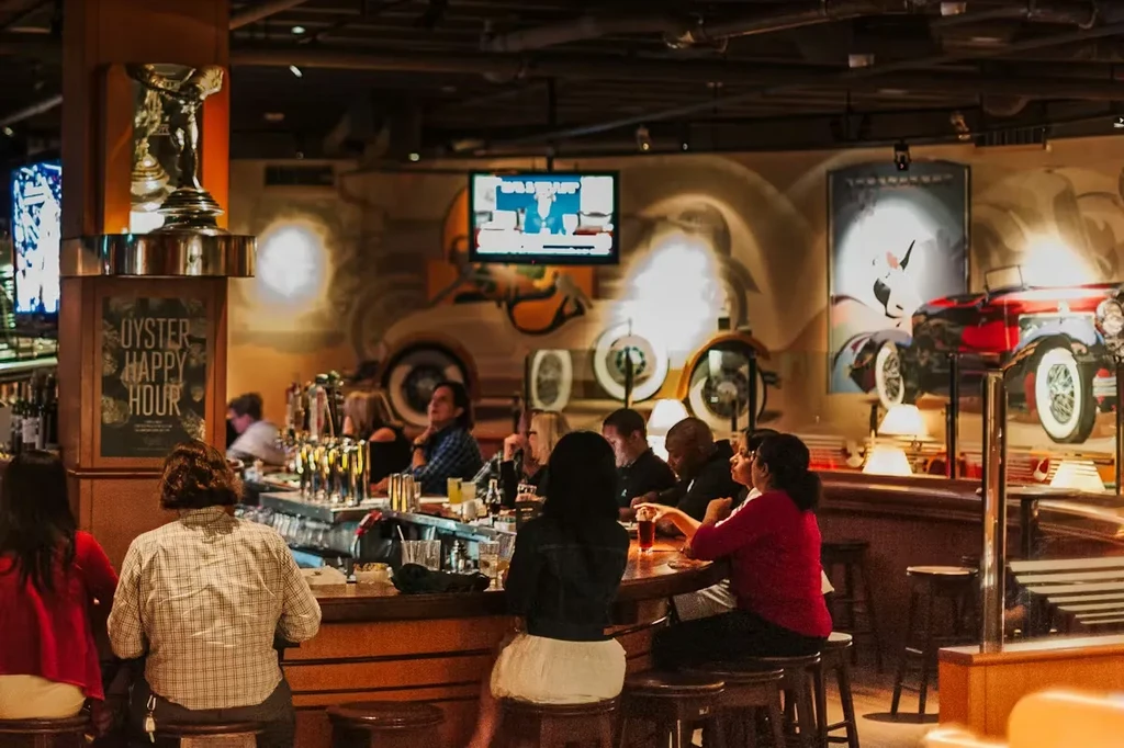 Busy bar interior with patrons, warm lighting, and unique wall art.