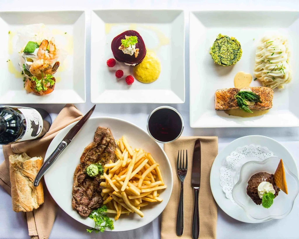 Overhead view of an elegantly set table with gourmet dishes and wine.