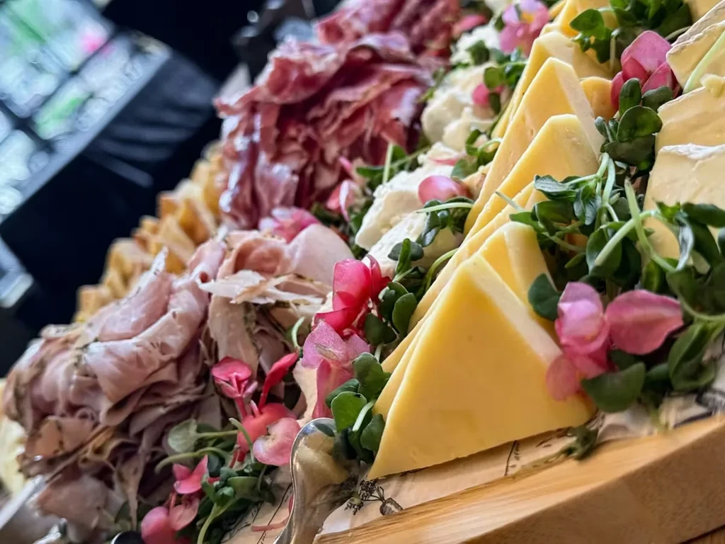 Elegant charcuterie and cheese board with meats, cheeses, and garnishes.
